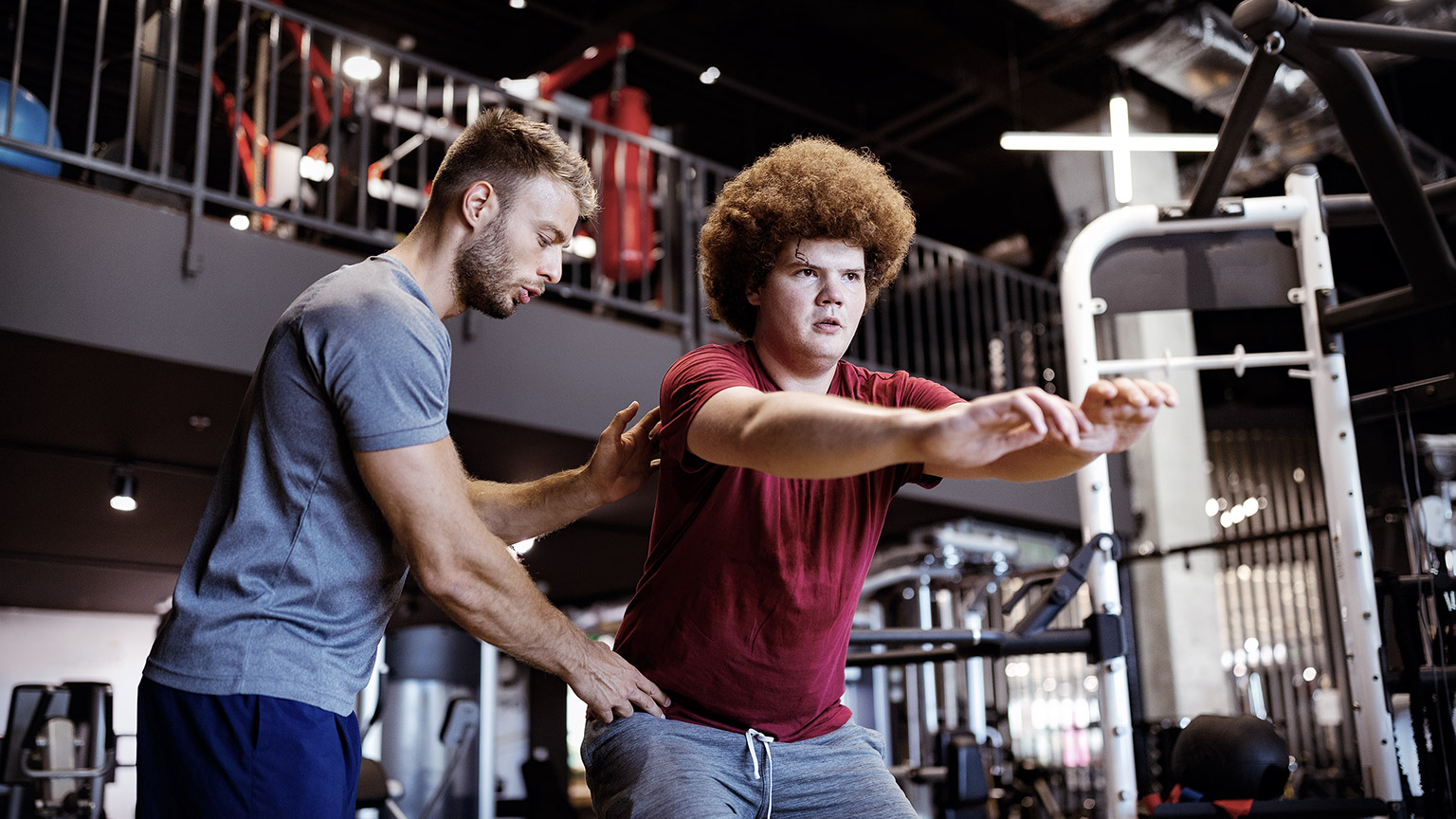 Overweight man guided by physical trainer