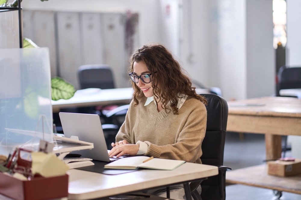 2223351425 Smiling female office worker using a laptop 