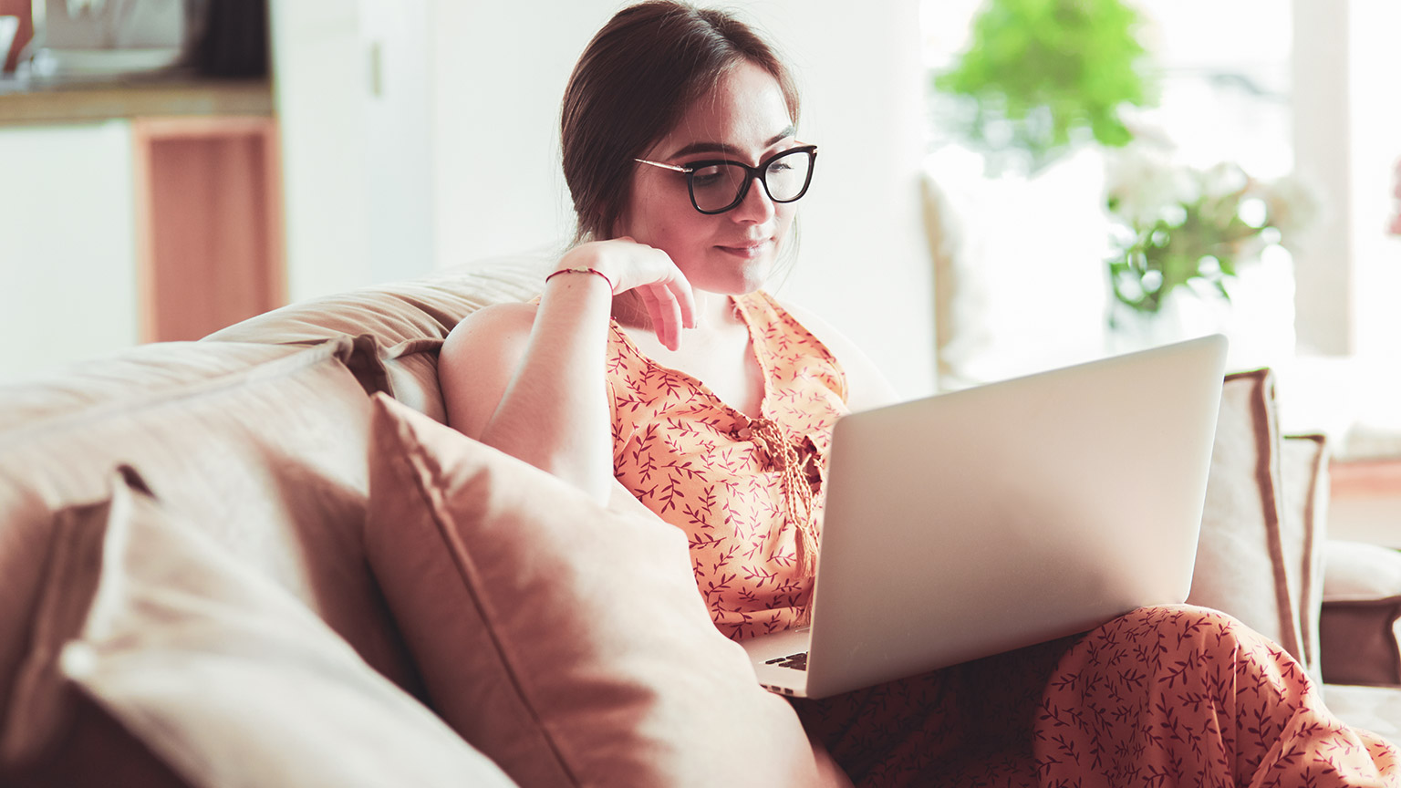 A person sitting on a couch reading information on a laptop