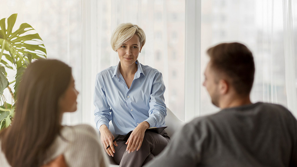 Psychologist Smiling Looking At Couple's Reconciliation During Therapy Session