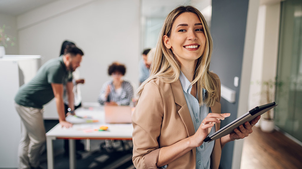 Smiling confident business leader looking at camera and standing in an office at team meeting