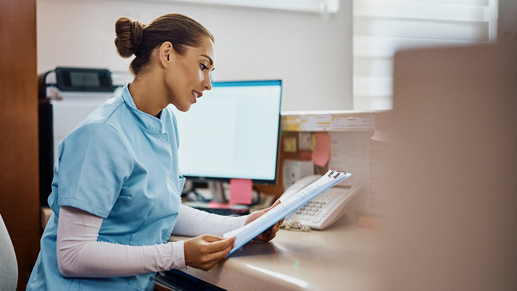 nurse reading medical reports while working at reception desk