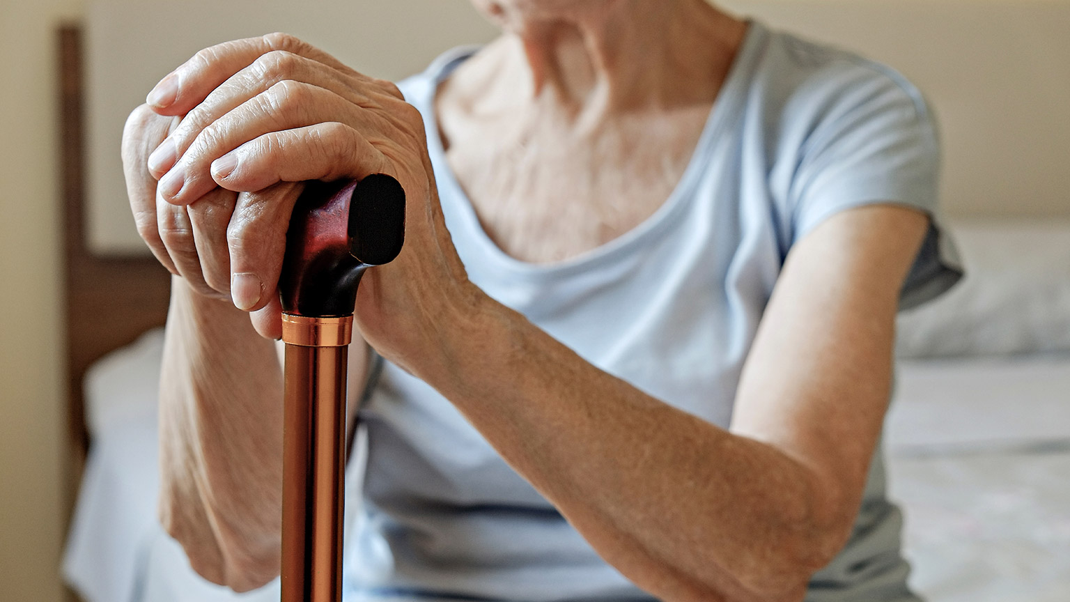 A close view of an elderly patient with a walking stick