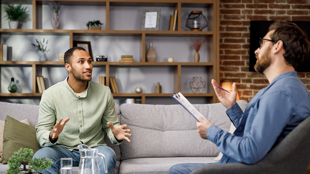 A man sits on a couch and talks to a psychotherapist