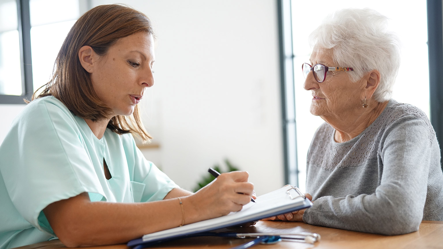 A carer talking to a client and writing down information