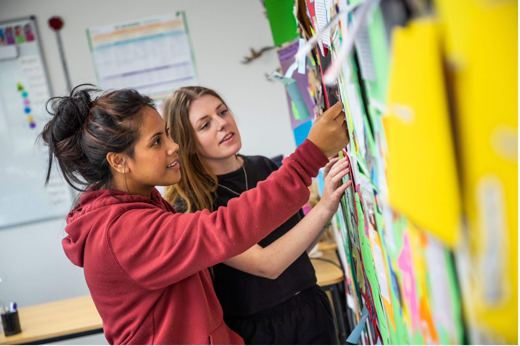 Two NZMA students look at notes on a wall.