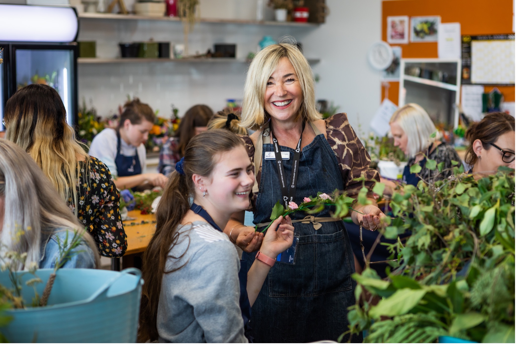 Tutor smiles at camera, in floristry class