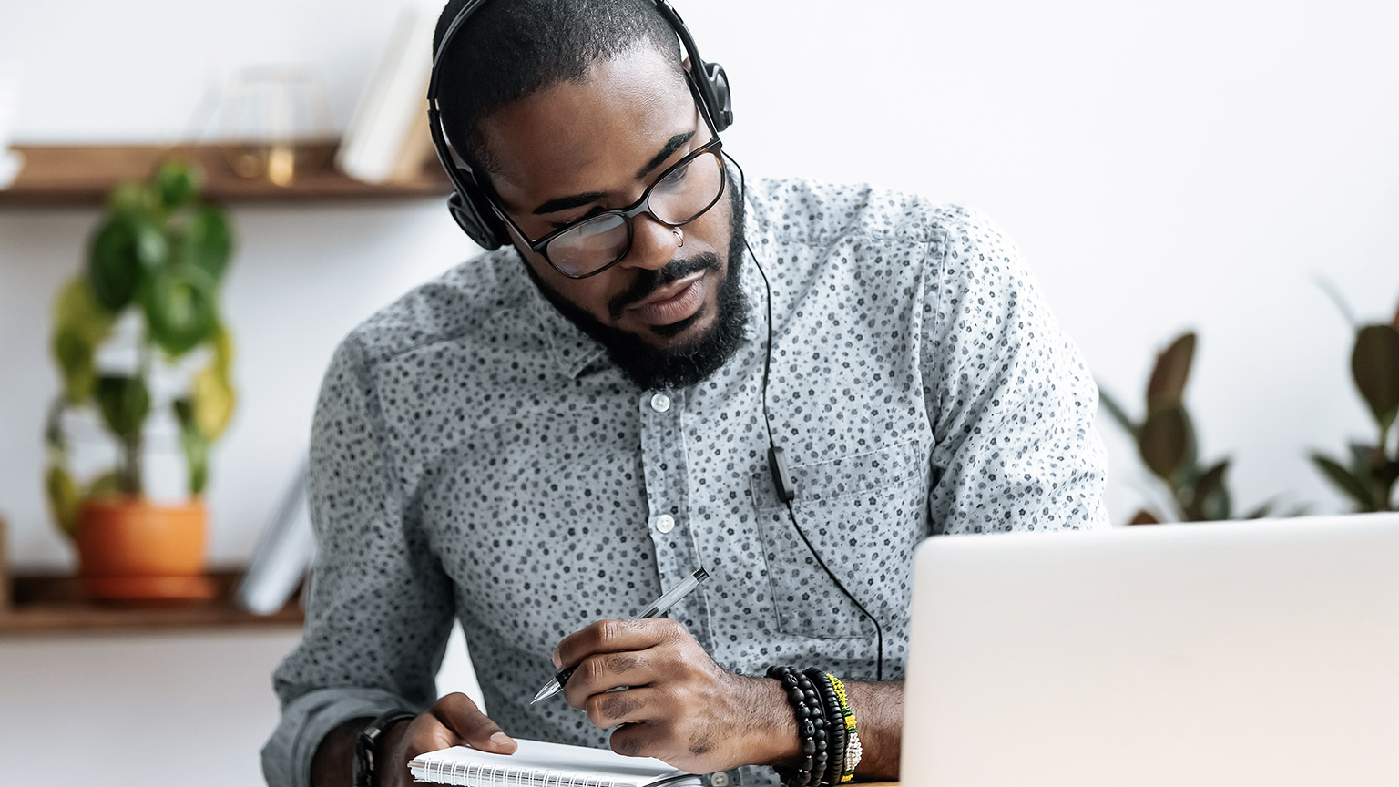 man on headphone writing notes