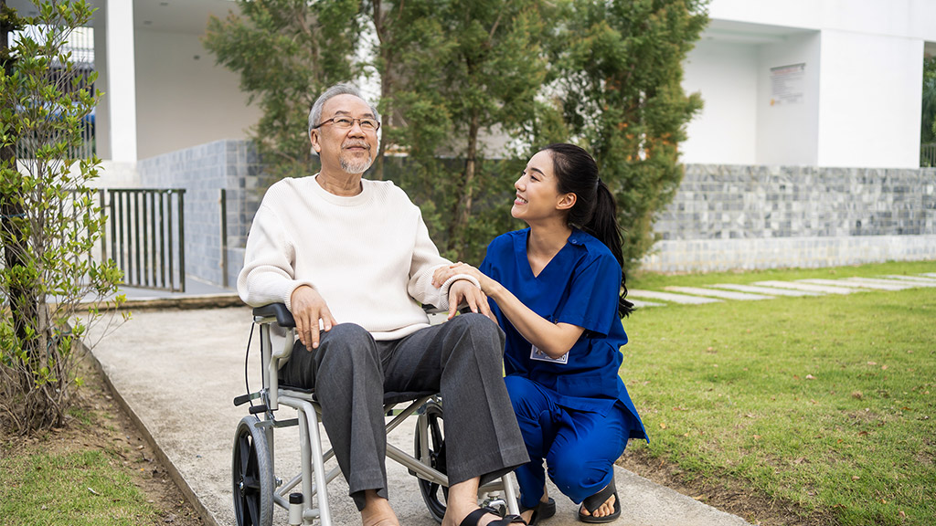 caregiver nurse take care senior male sit on wheelchair outdoor