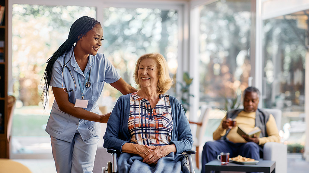 senior woman in wheelchair and young healthcare worker in nursing home