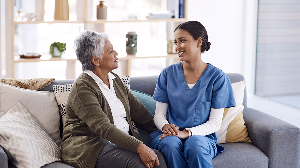 nurse talking to an old woman on a sofa in the living room