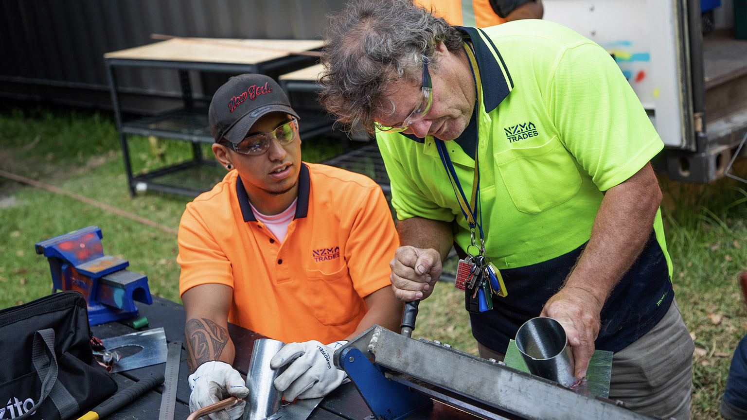 A tradesman showing an apprentice how to build stuff