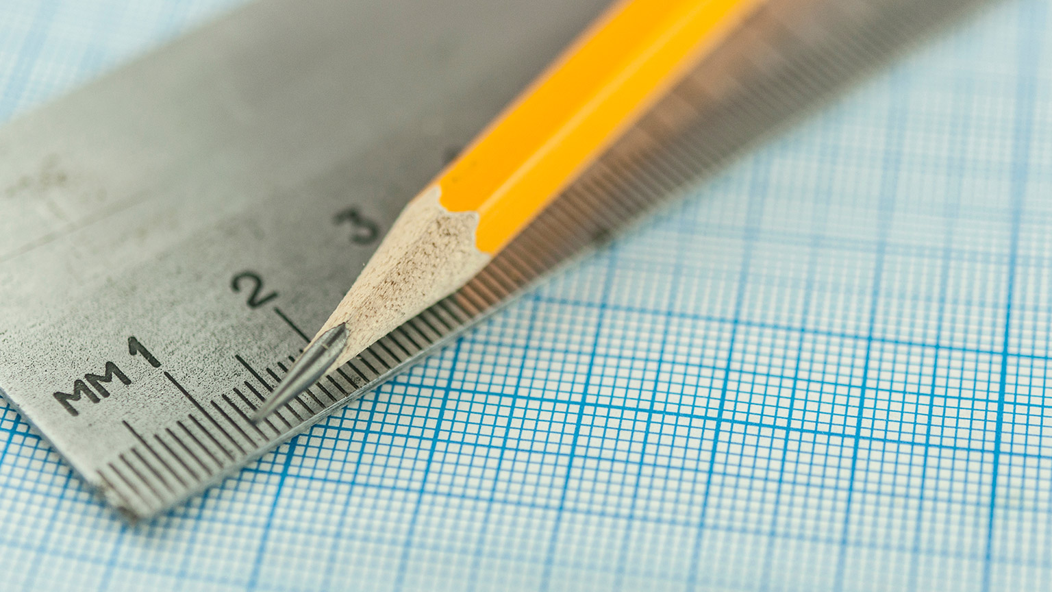 A close view of a pencil, ruler and grid paper