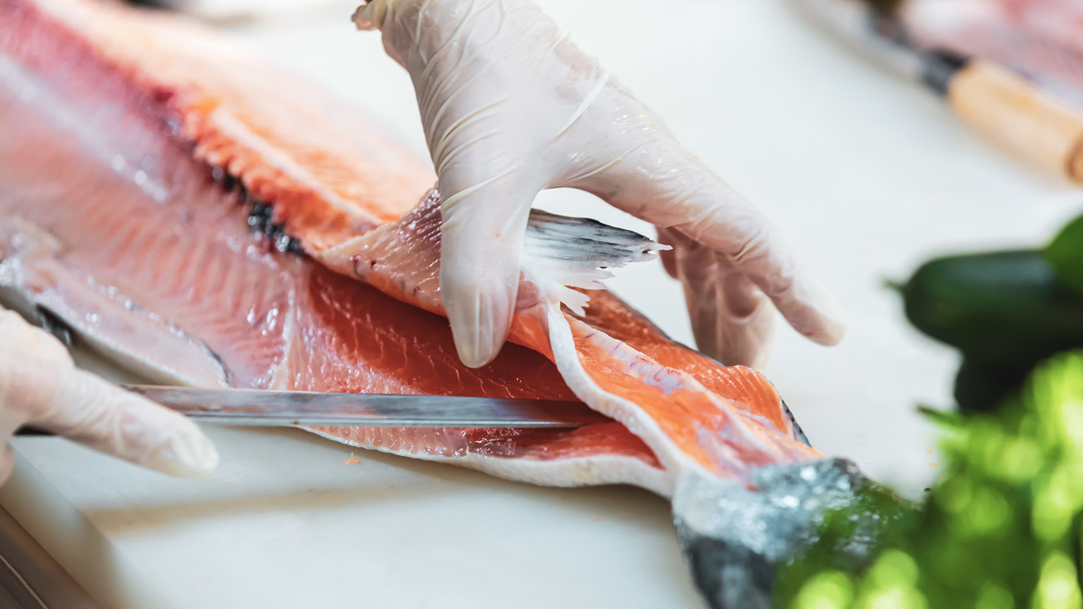 A chef cutting salmon with a sharp knife