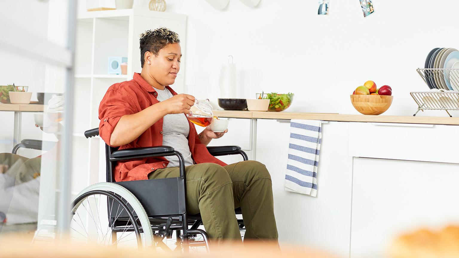 A person in a wheelchair pouring themselves a cup of tea