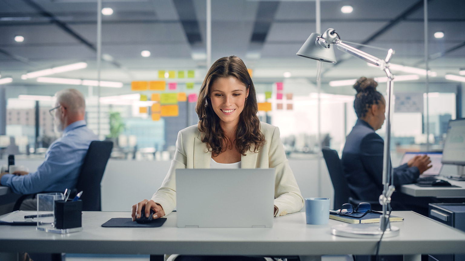 young happy woman using computer in modern office with colleagues