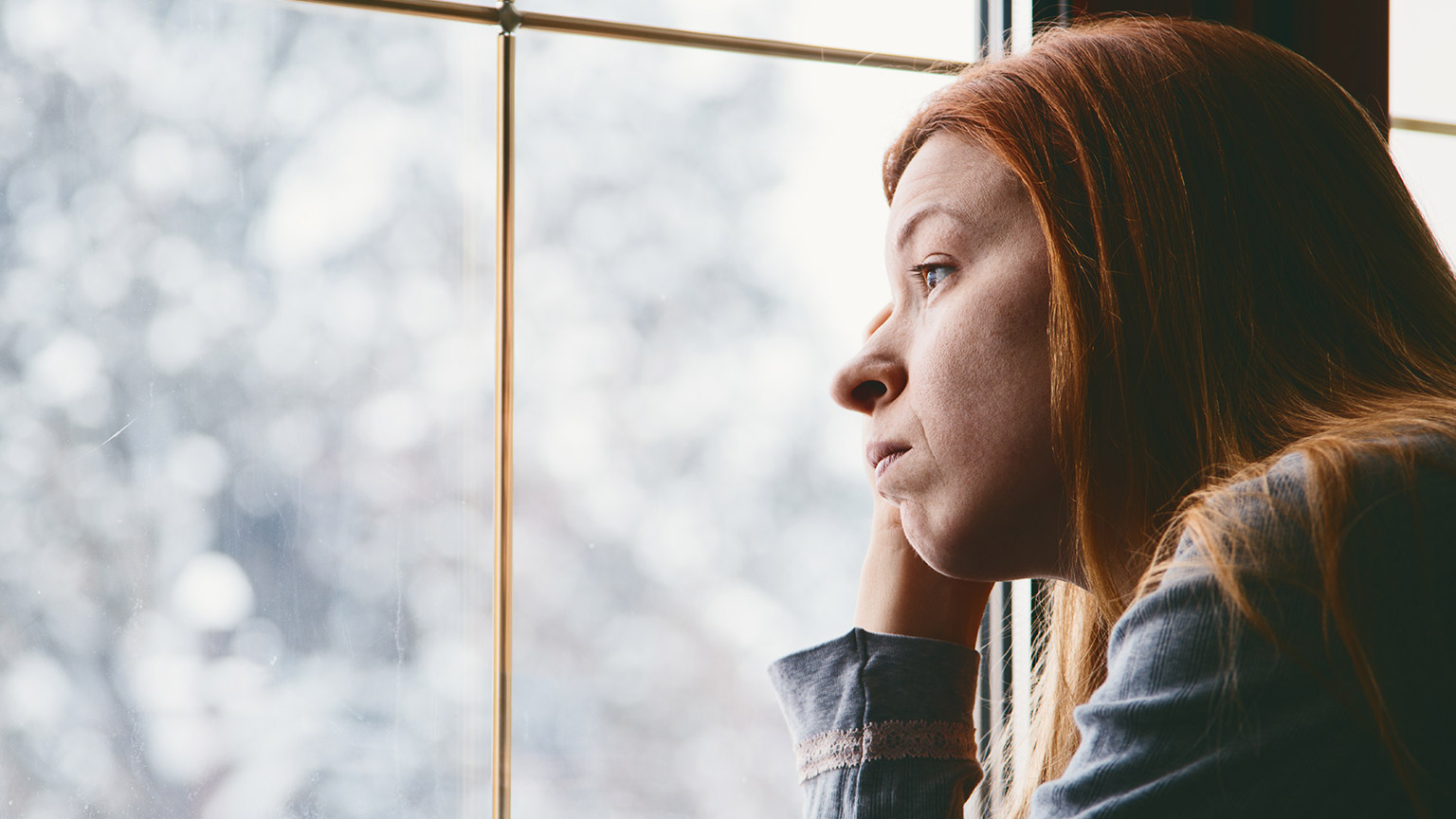 A sad person looking out a window