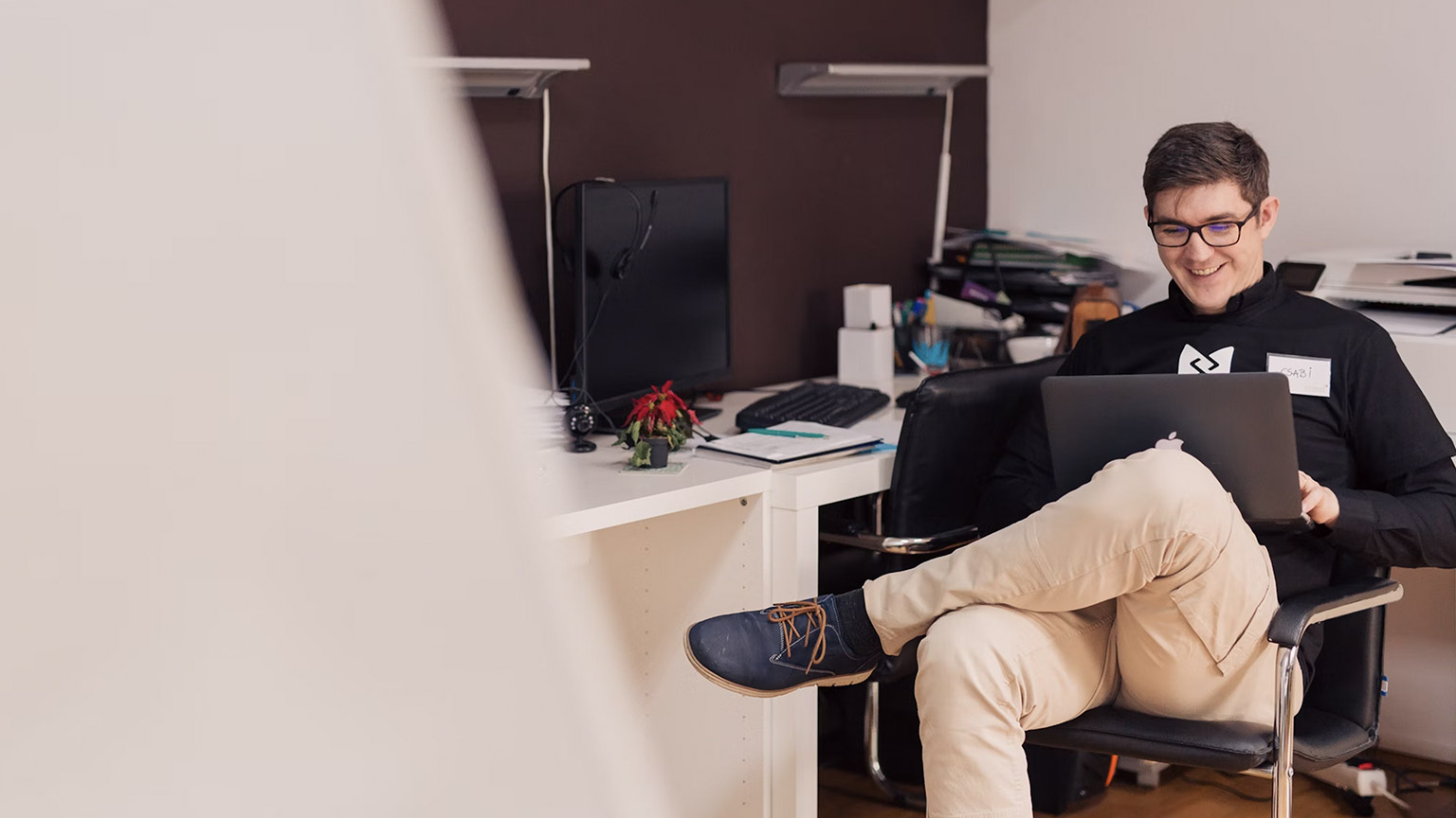 man using laptop and sitting comfortably in his office workspace