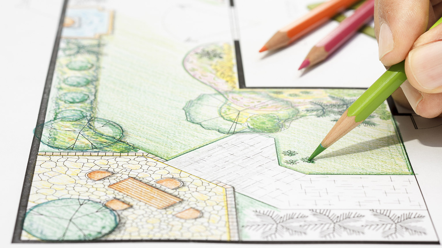 Fingers holding drawing a landscape design in colored pencils