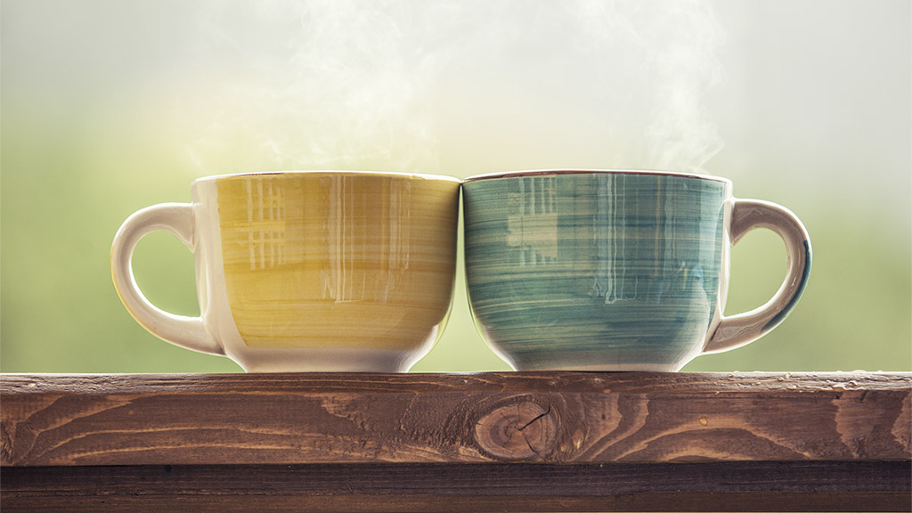 Mugs with a hot drink with tea on a wooden stand outdoors in the countryside