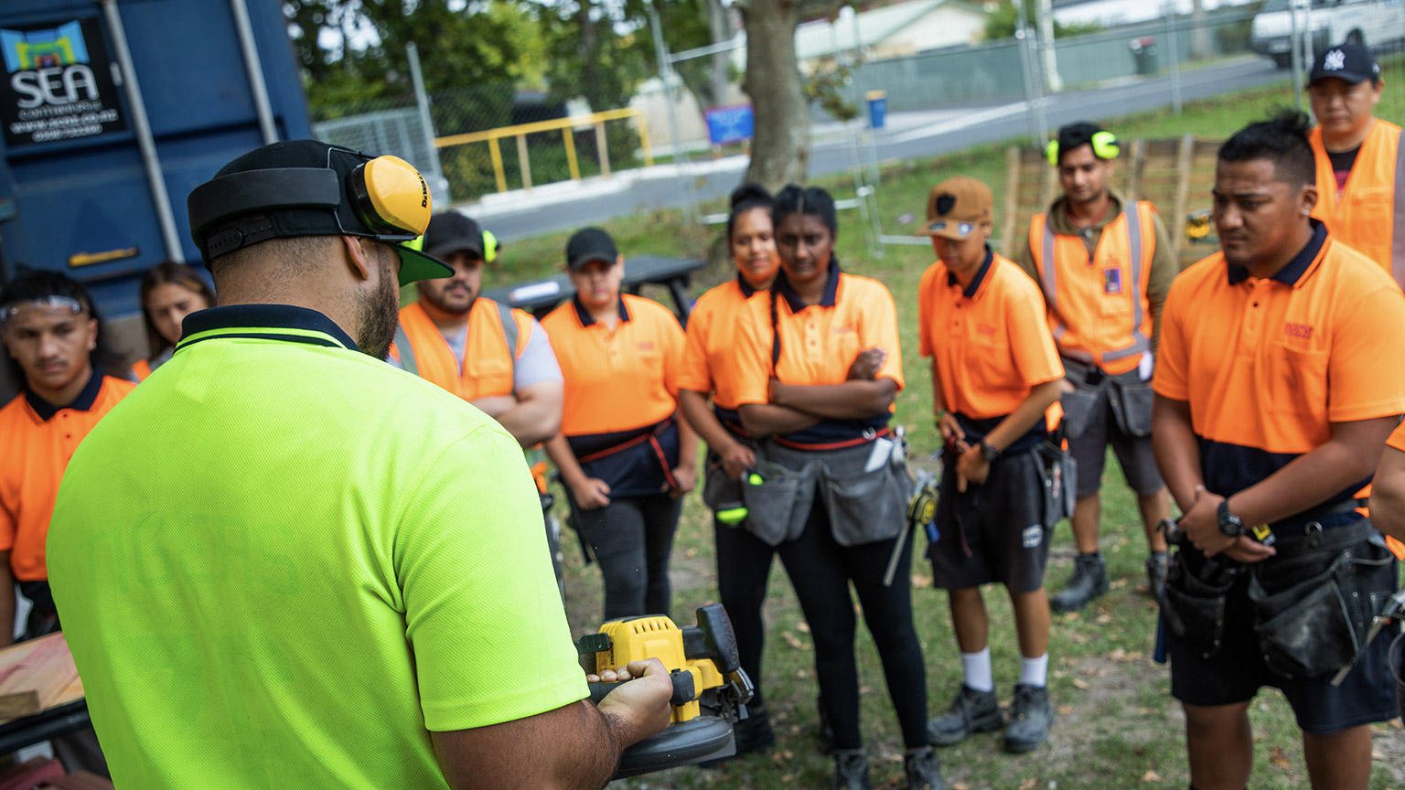 A tradesman demonstrating something to a group of apprentices