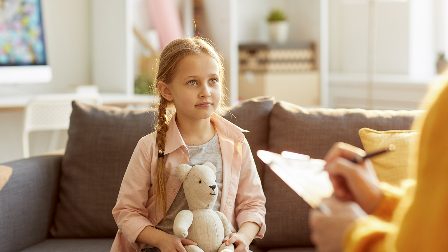 Portrait of cute little girl listening to psychologist during therapy session on youth issues