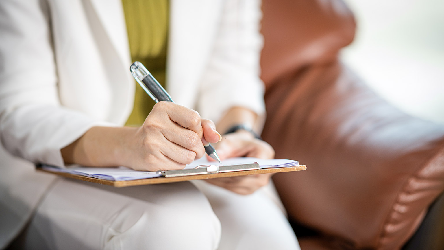 Psychologist making notes in medical history while understanding problems of a woman patient