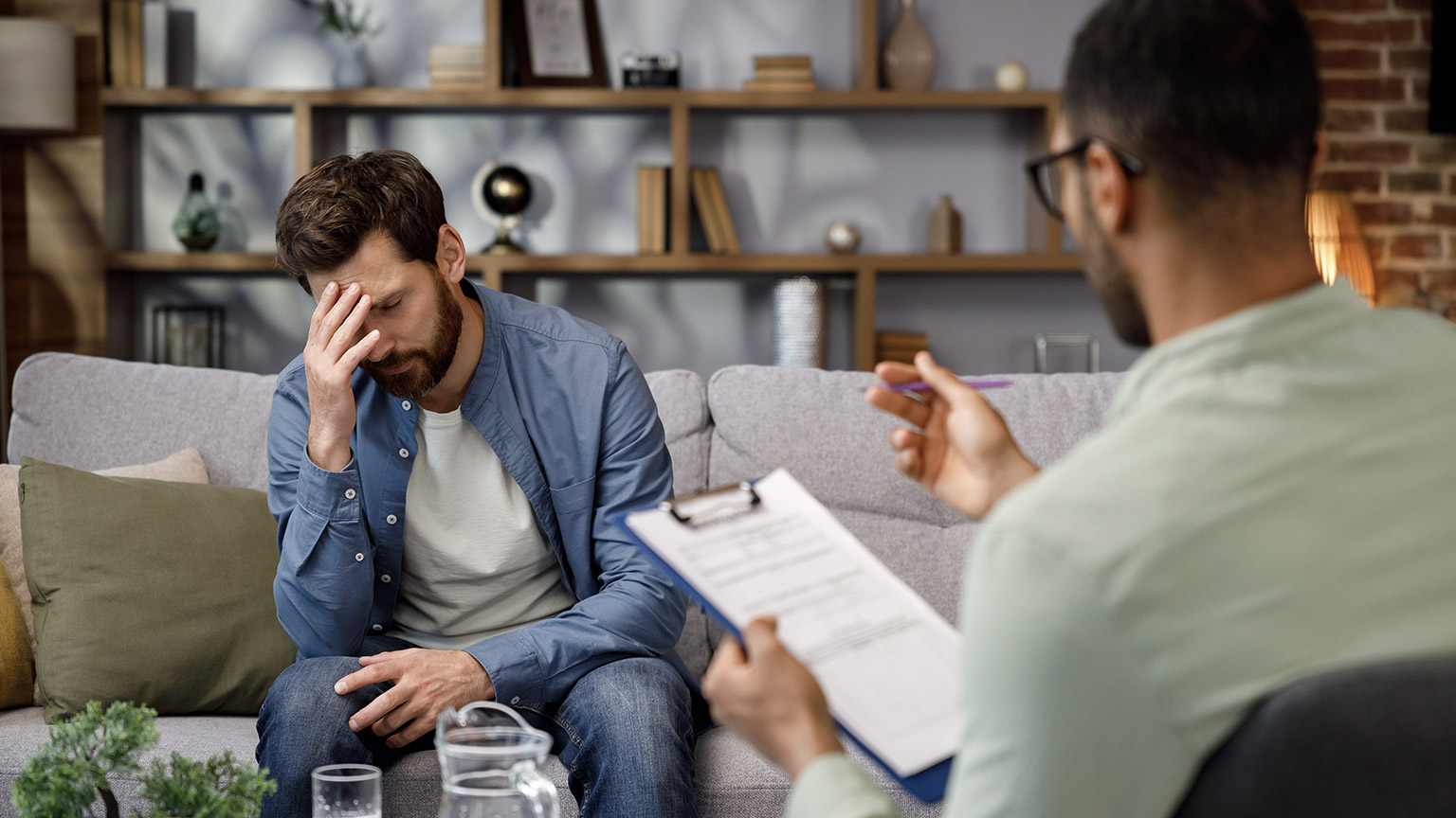 Visit to a psychologist. A man sits on a couch and talks to a psychotherapist.