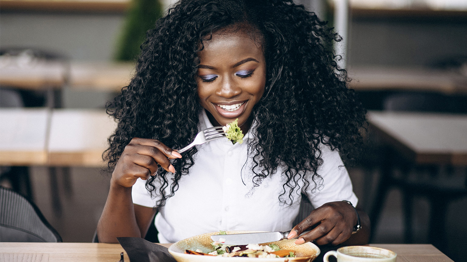 African american business woman eating salad in a cafe