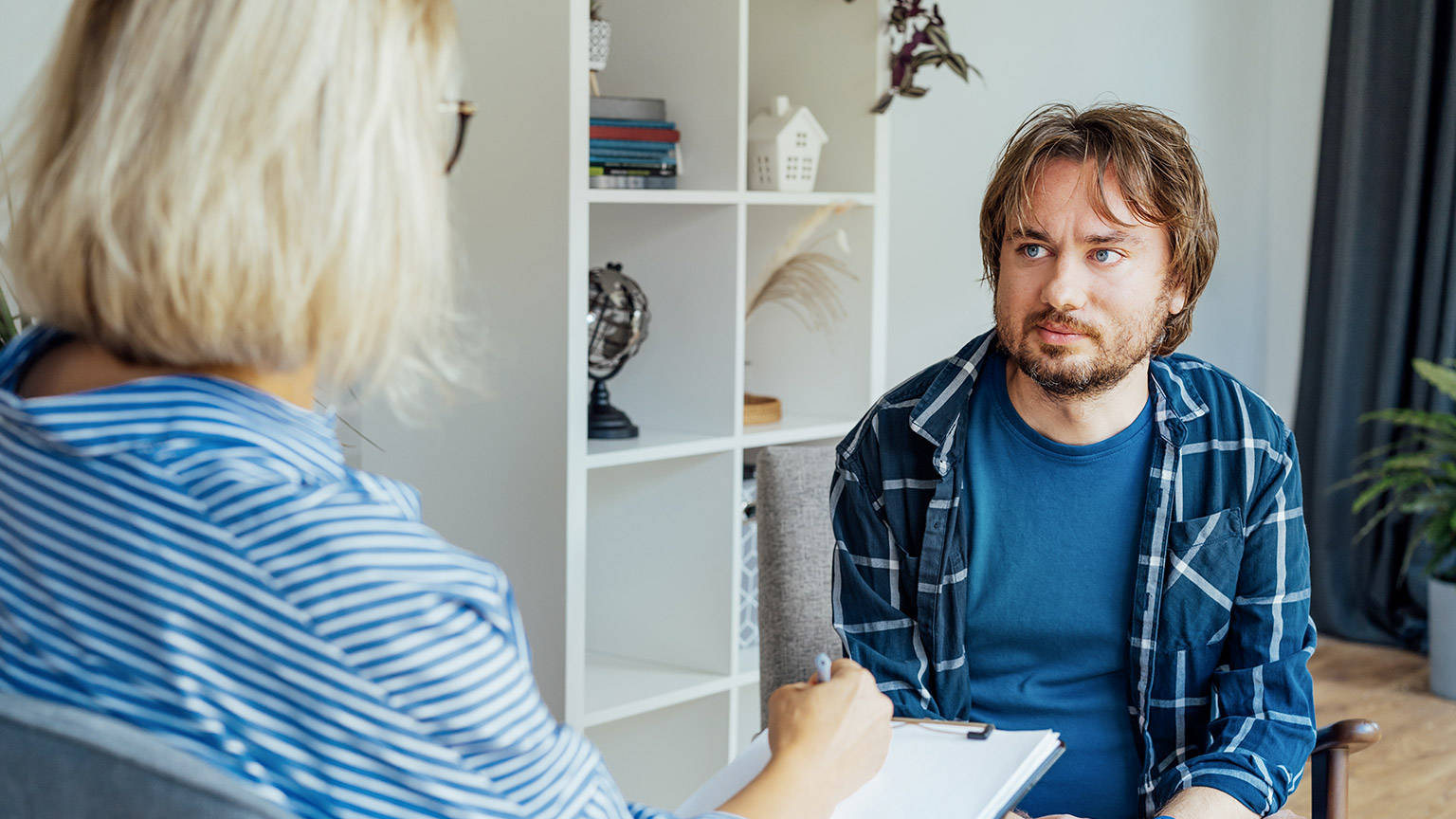 Depressed male patient having psychotherapy session with counselor at mental health clinic.