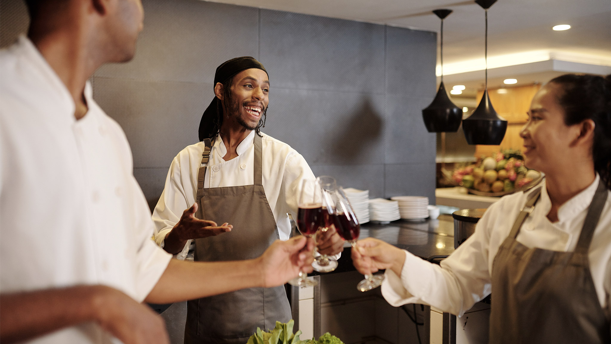 Team of joyful cooks drinking wine when celebrating 