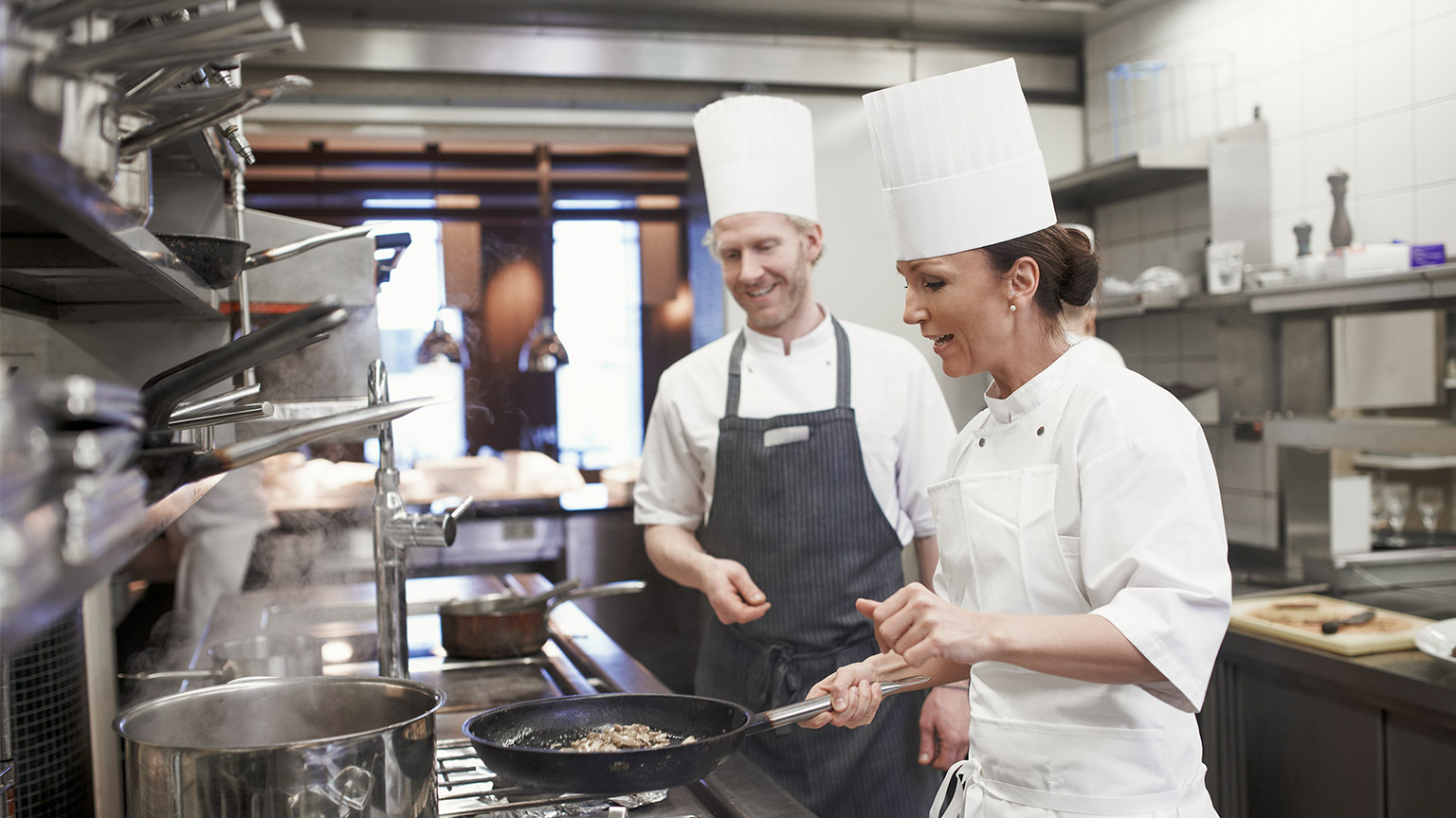 Teamwork, meat and chef with frying pan in kitchen for catering service