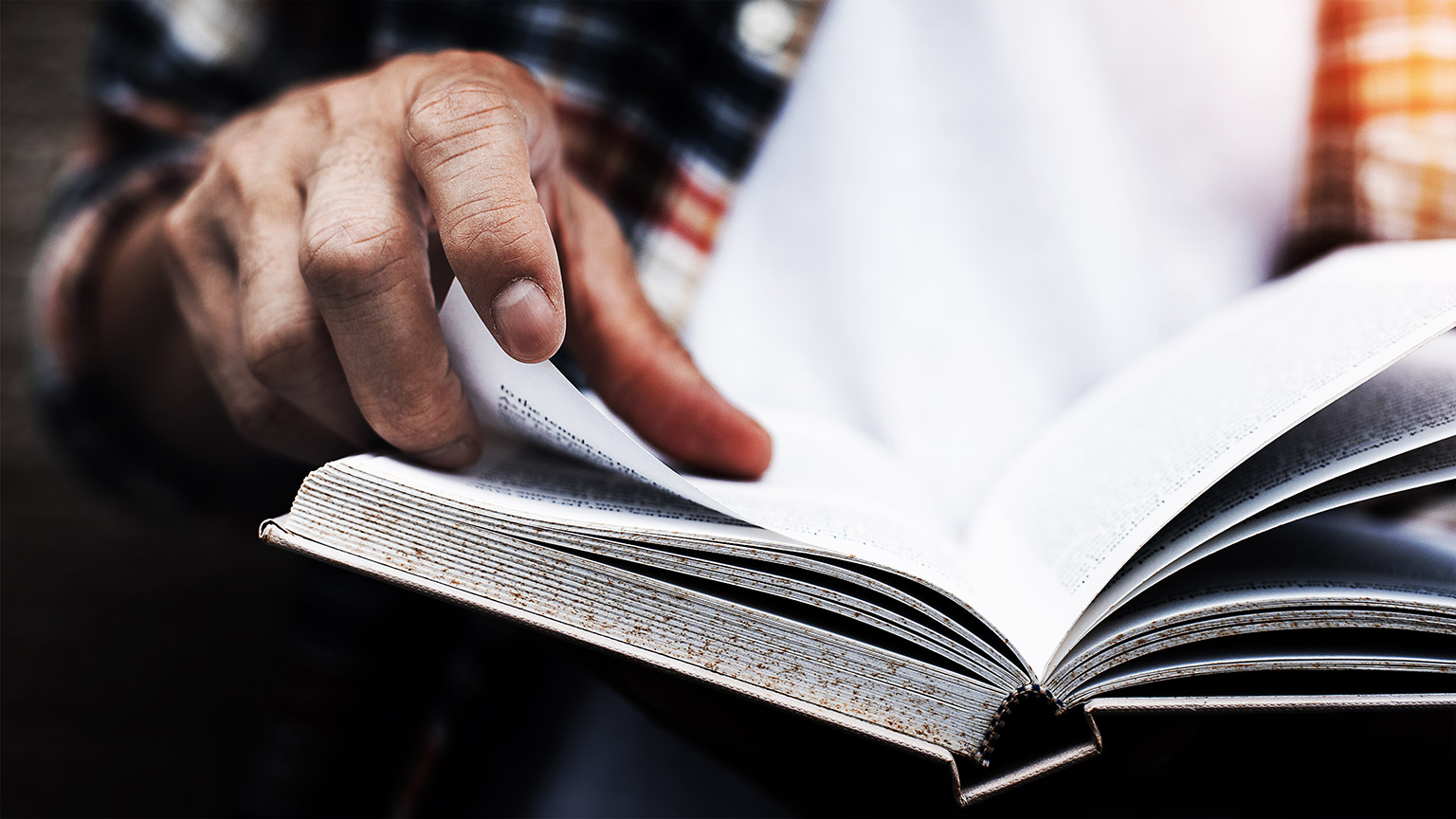 man opening and reading a book, close up, vintage style.