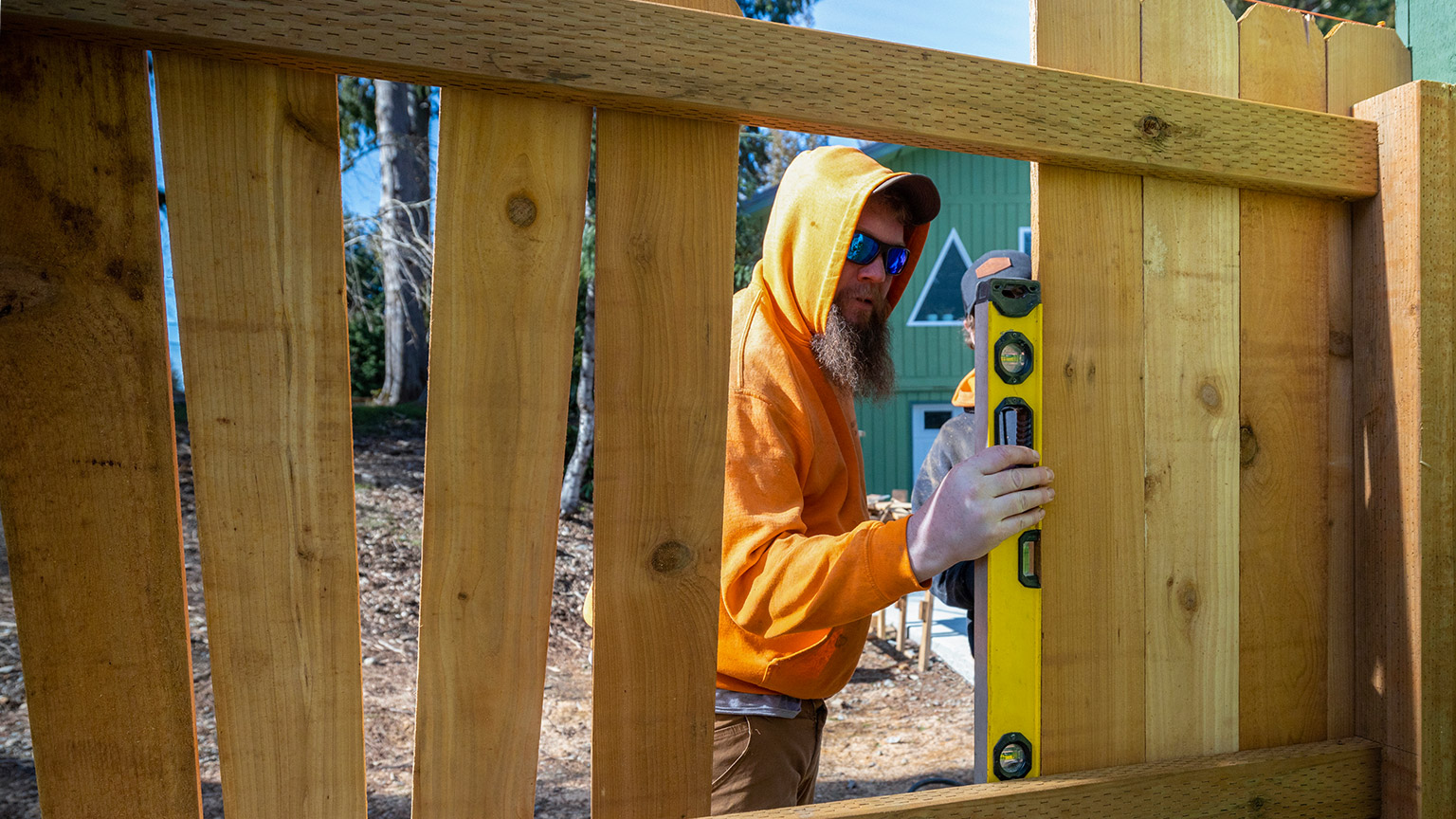 A person constructing a fence in a backyard