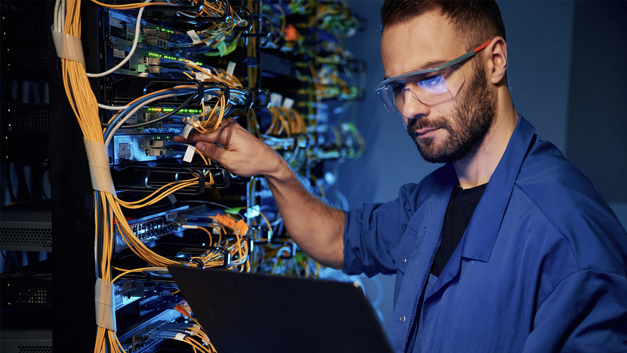 Young man is working with internet equipment and wires in server room