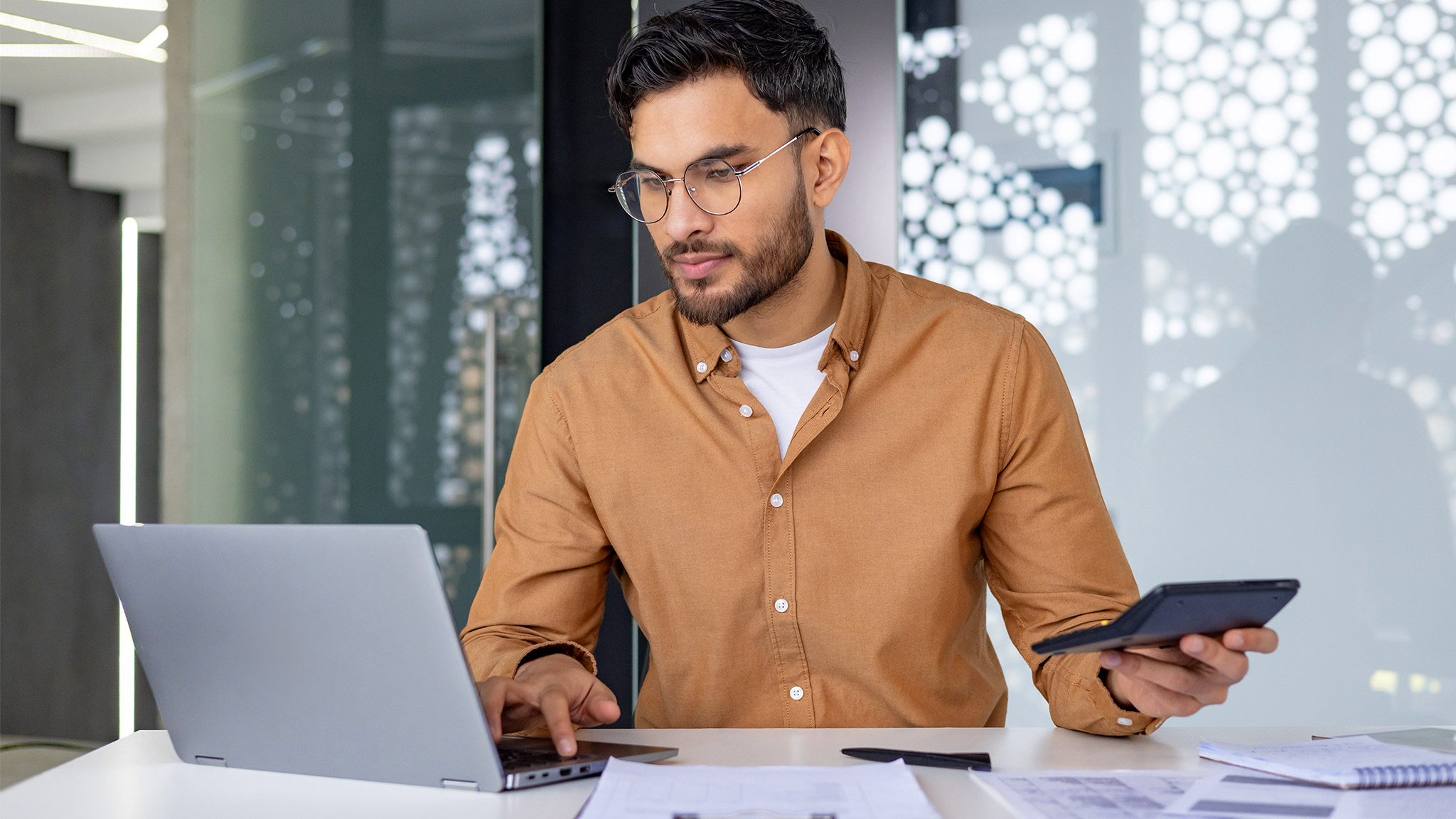 Indian man working in the office on a laptop with data and accounting