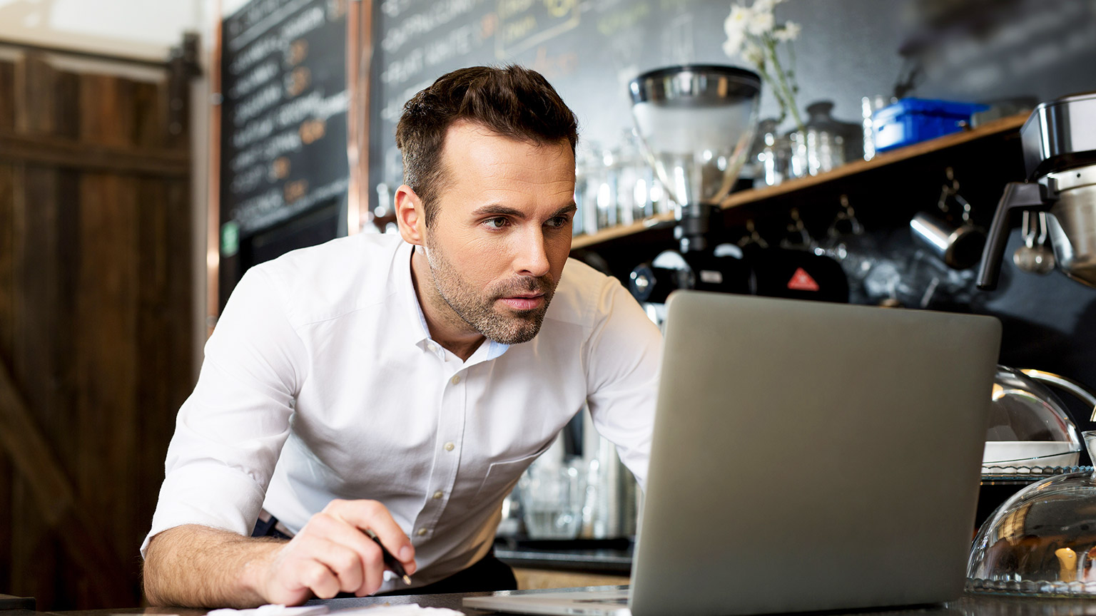 Restaurant manager working on laptop, counting profit