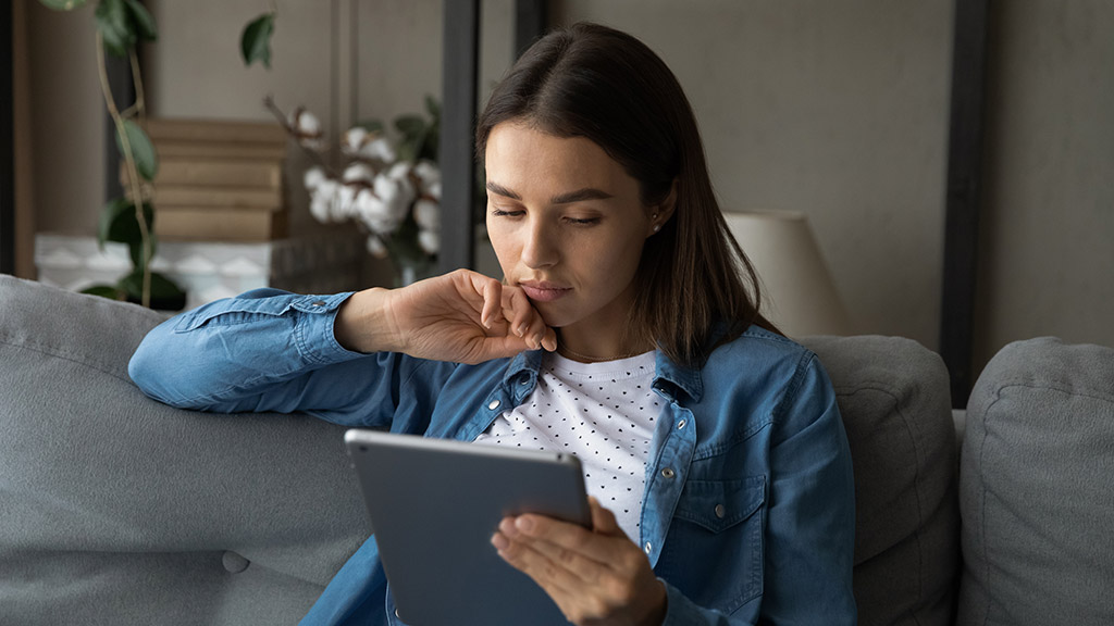 Young serious woman sit on sofa spend free time use modern wireless tech