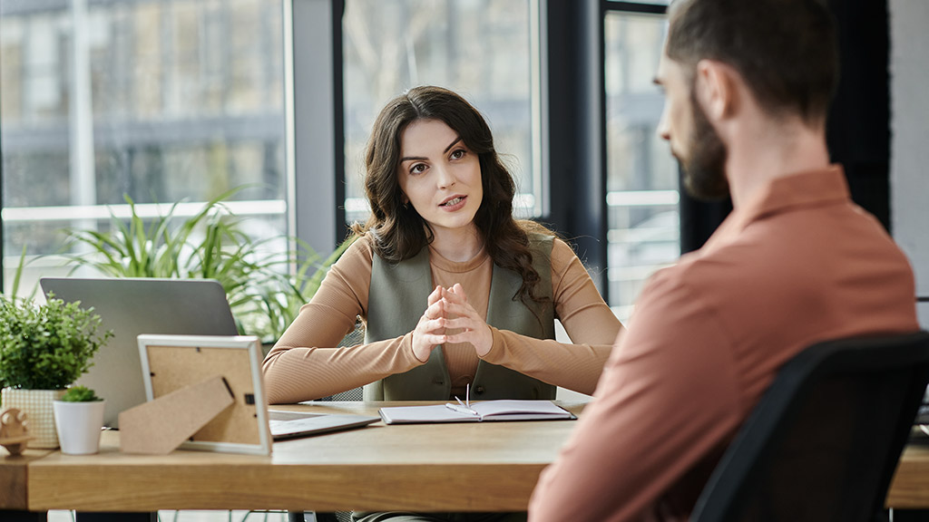 Colleagues converse thoughtfully amid layoffs in a bright, contemporary workspace.