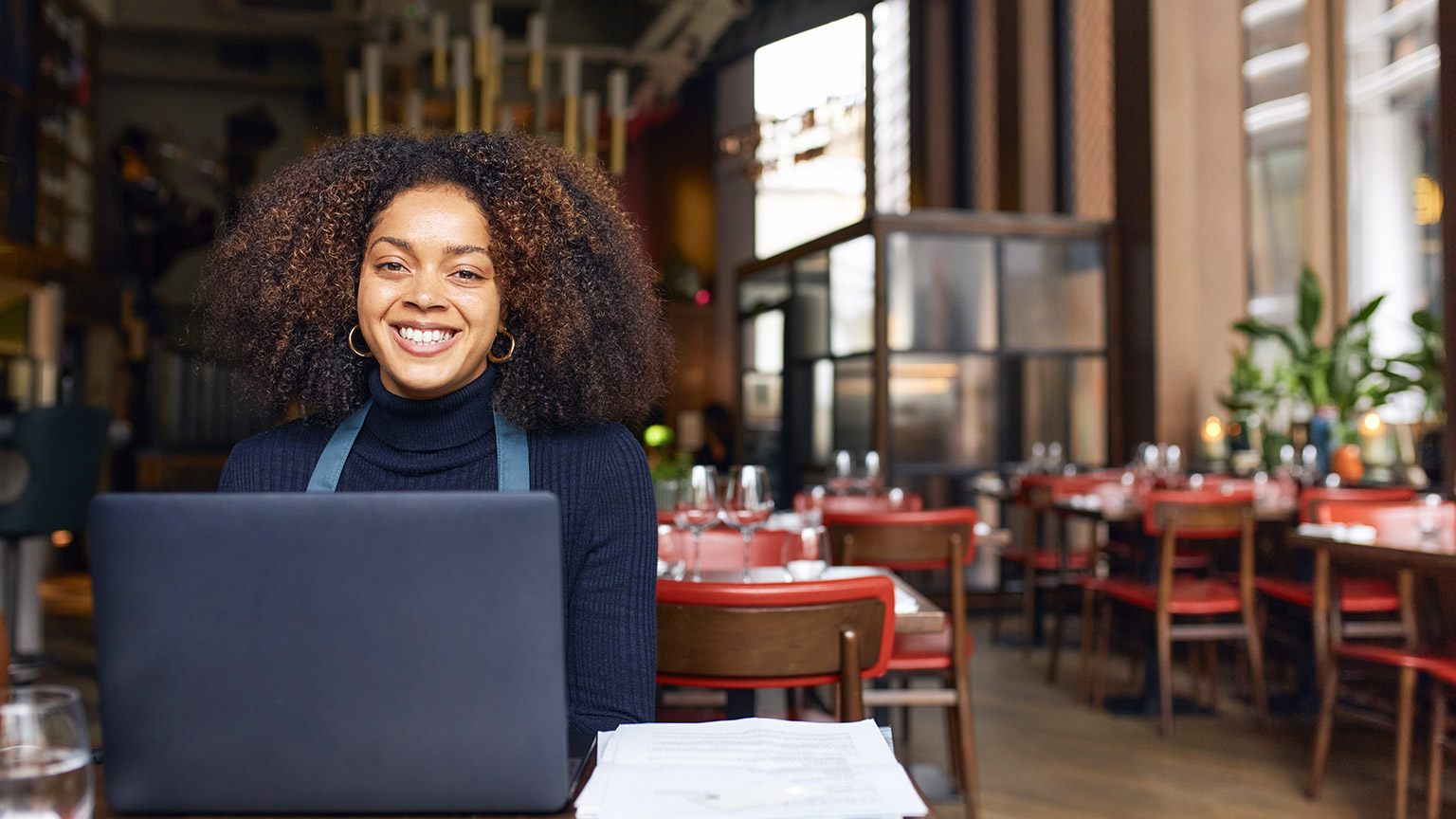 Portrait of cheerful restaurant owner with laptop