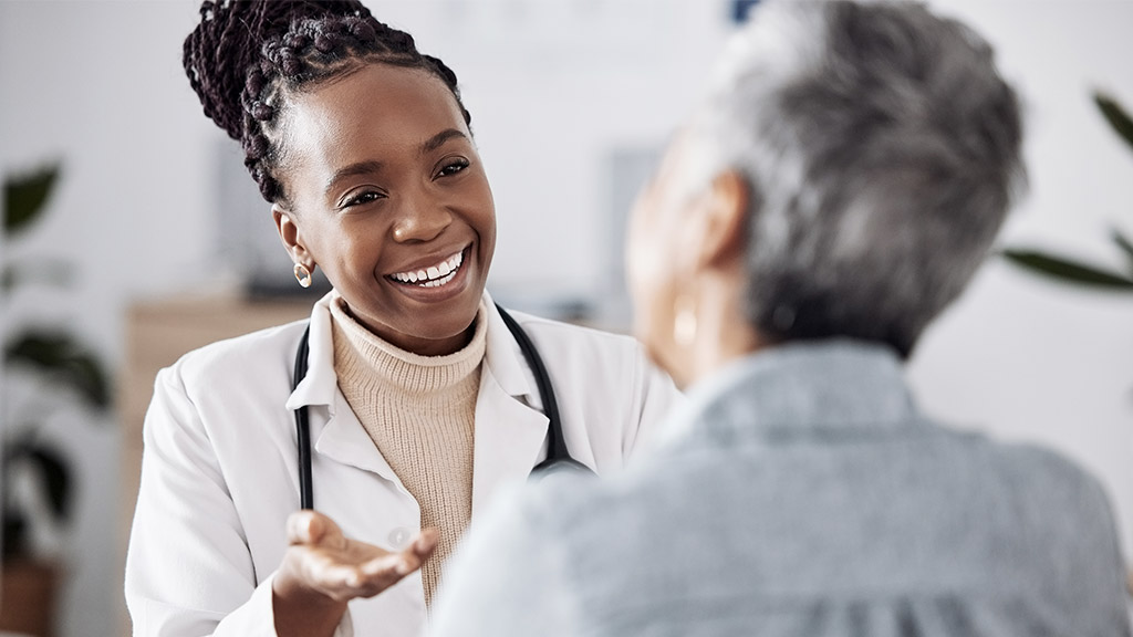 Smile, black woman or doctor consulting a patient in meeting in hospital for healthcare feedback or support