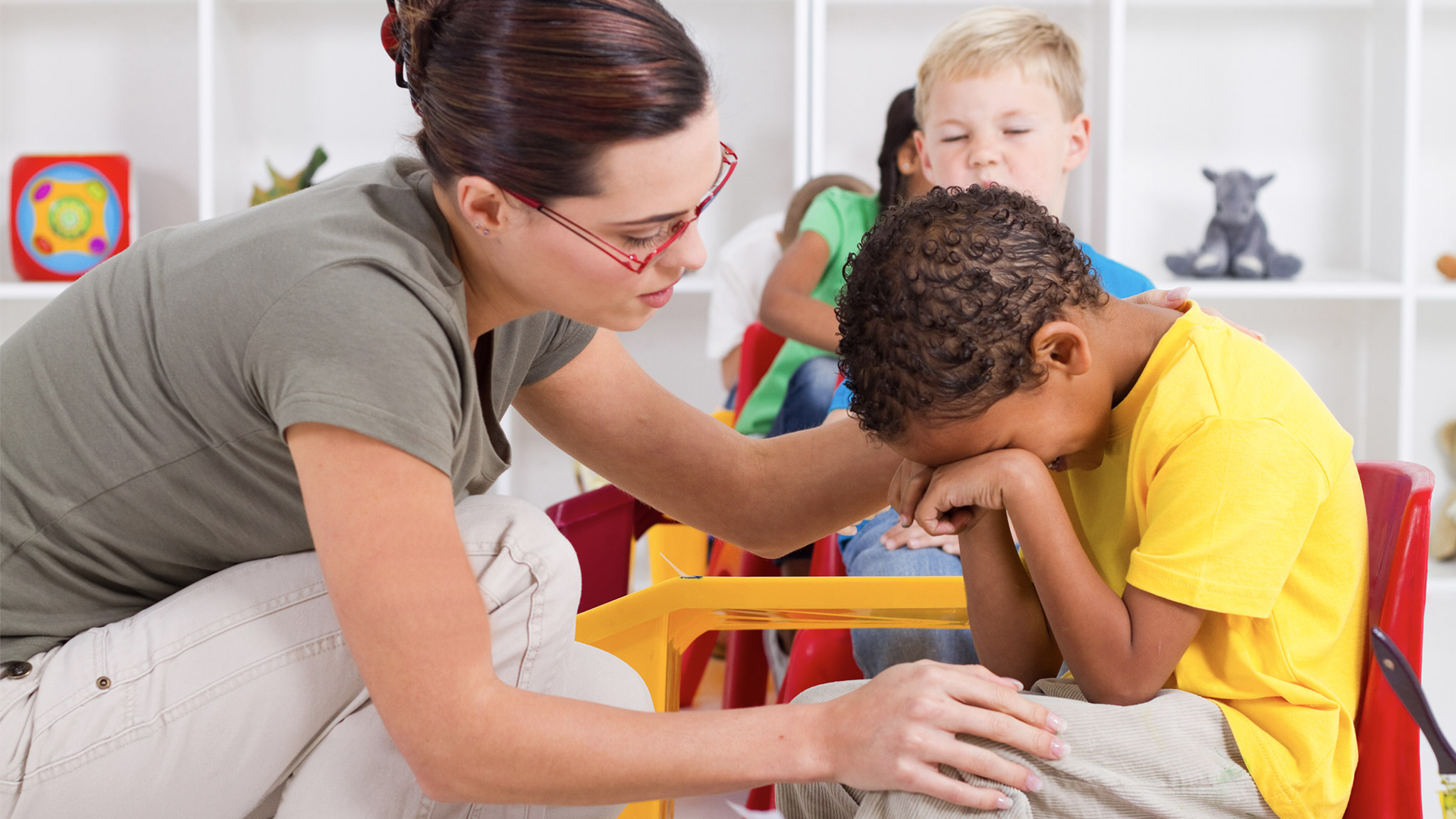 teacher comforting crying preschool boy