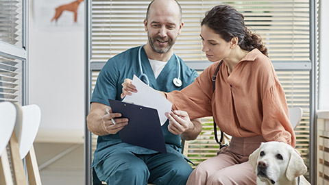 young woman talking to smiling veterinarian in waiting room at vet clinic