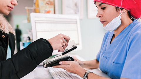 Young woman paying in a veterinary with credit card