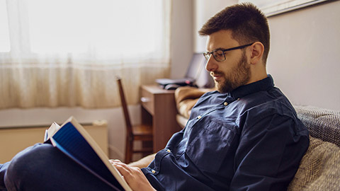 man reading a book while sitting on a couch