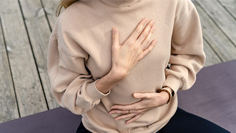 Close-up of a woman's hands on her chest while doing breathing exercises