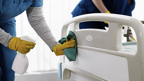 Team of professional janitors using equipment disinfecting hospital ward. Nurses in uniform cleaning furniture in empty clinic room. Healthcare and hygiene concept