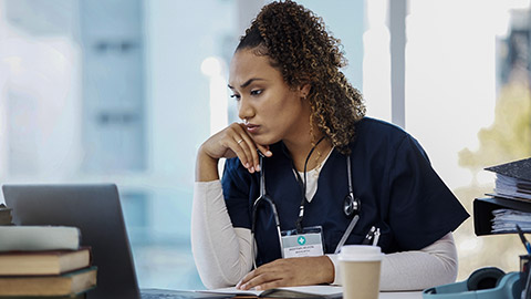 a studying nurse using a book and a laptop