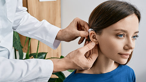 Installation hearing aid on woman's ear at clinic