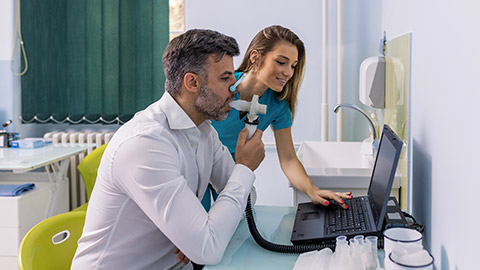 man testing breathing function by spirometry having health problem assisted by a nurse